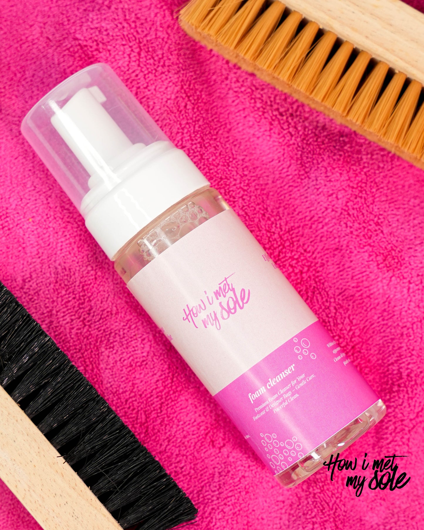 Bottle of 'How I Met My Sole' foam cleaner on a pink towel with brushes.