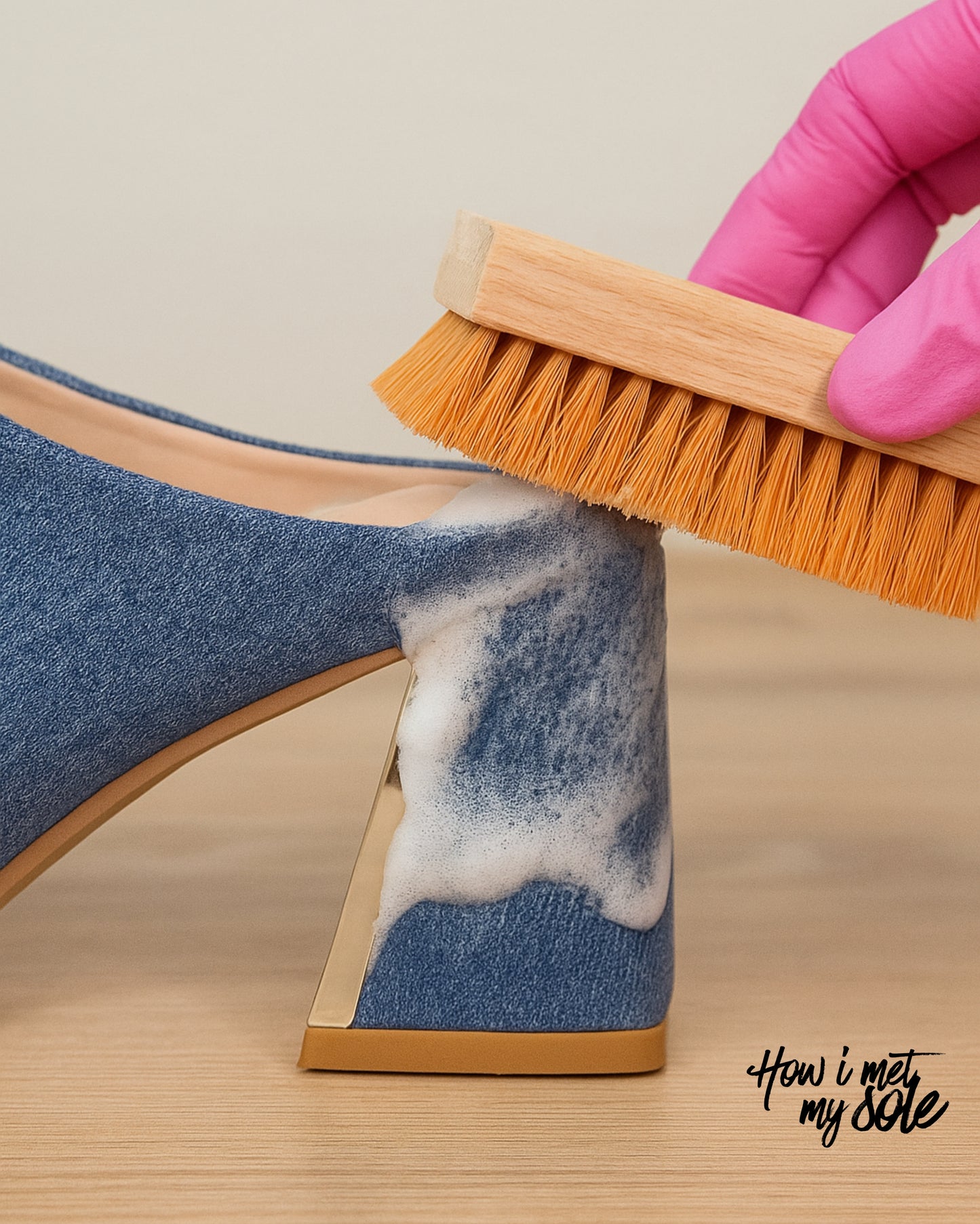 Cleaning a blue denim heel with a brush and foam cleaner