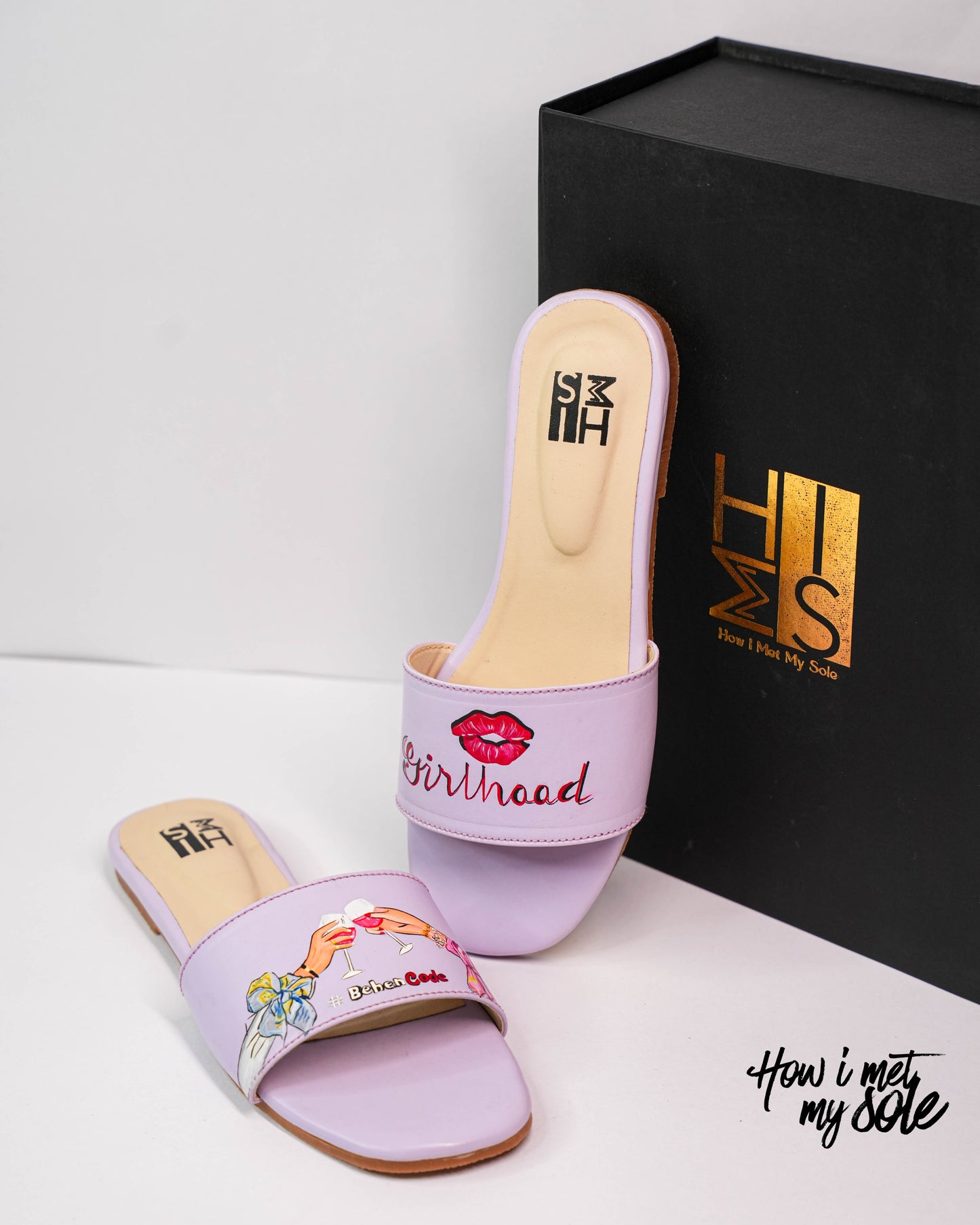 Pair of purple slides with floral design and 'Girlhood' text, next to a black box with 'HIMMS' branding.