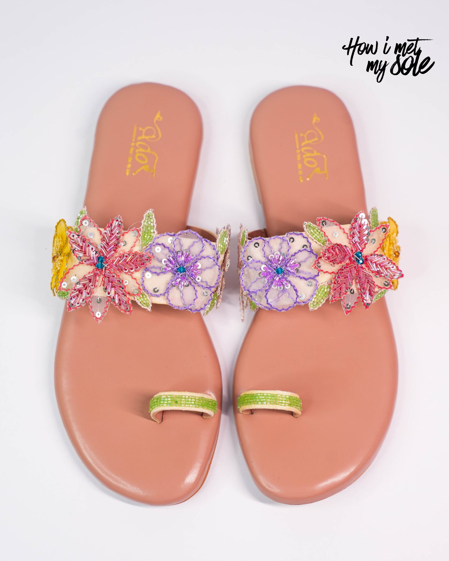 Pair of pink sandals with floral embellishments on a white background