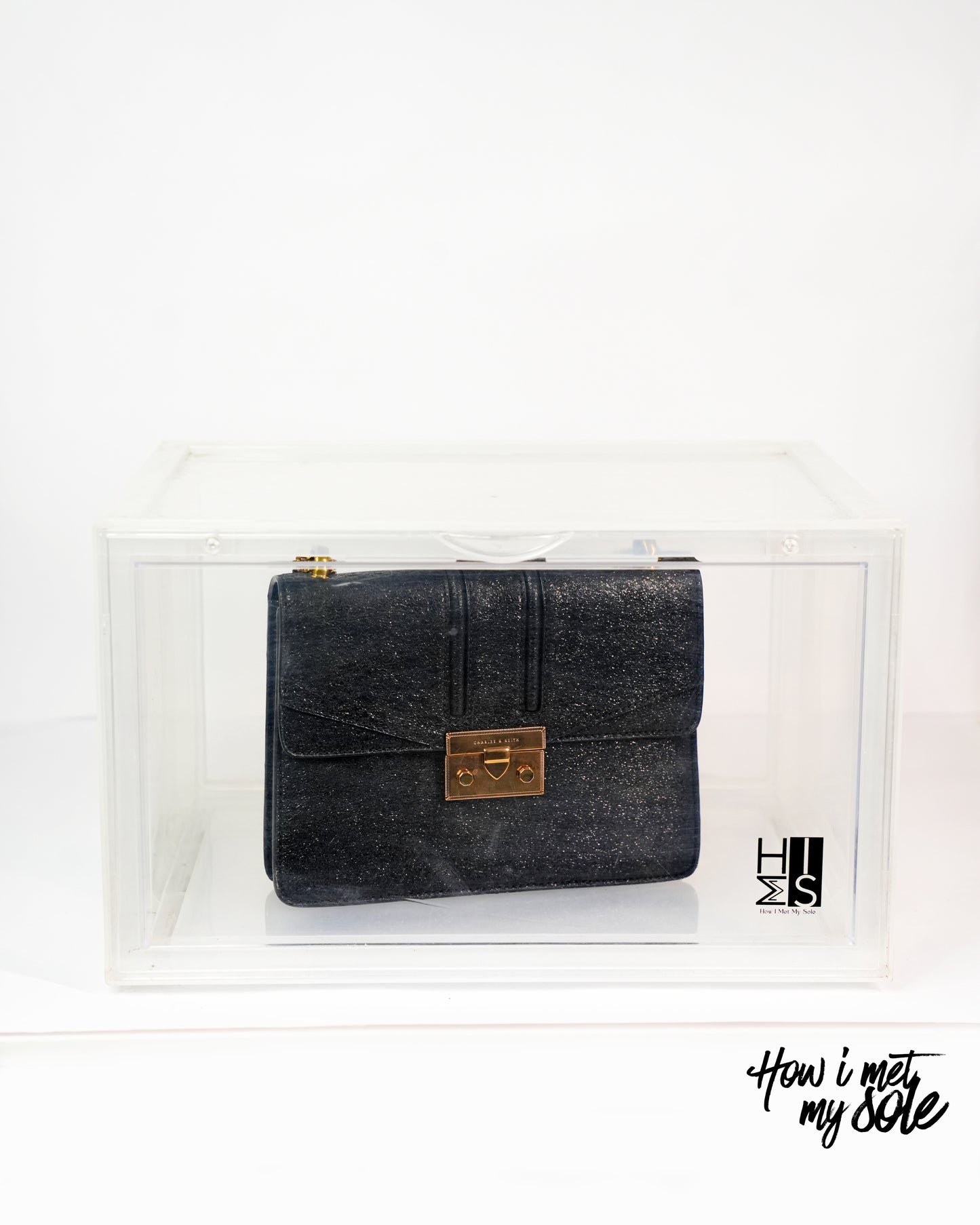 Black clutch bag with gold clasp in a style safe storage on a white background