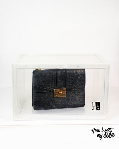 Black clutch bag with gold clasp in a style safe storage on a white background