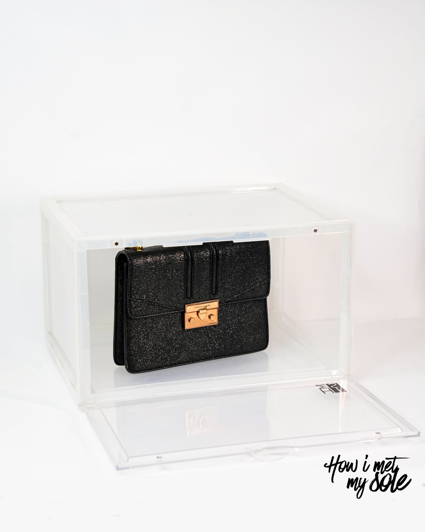 Black clutch bag with gold clasp in a clear style safe storage on a white background