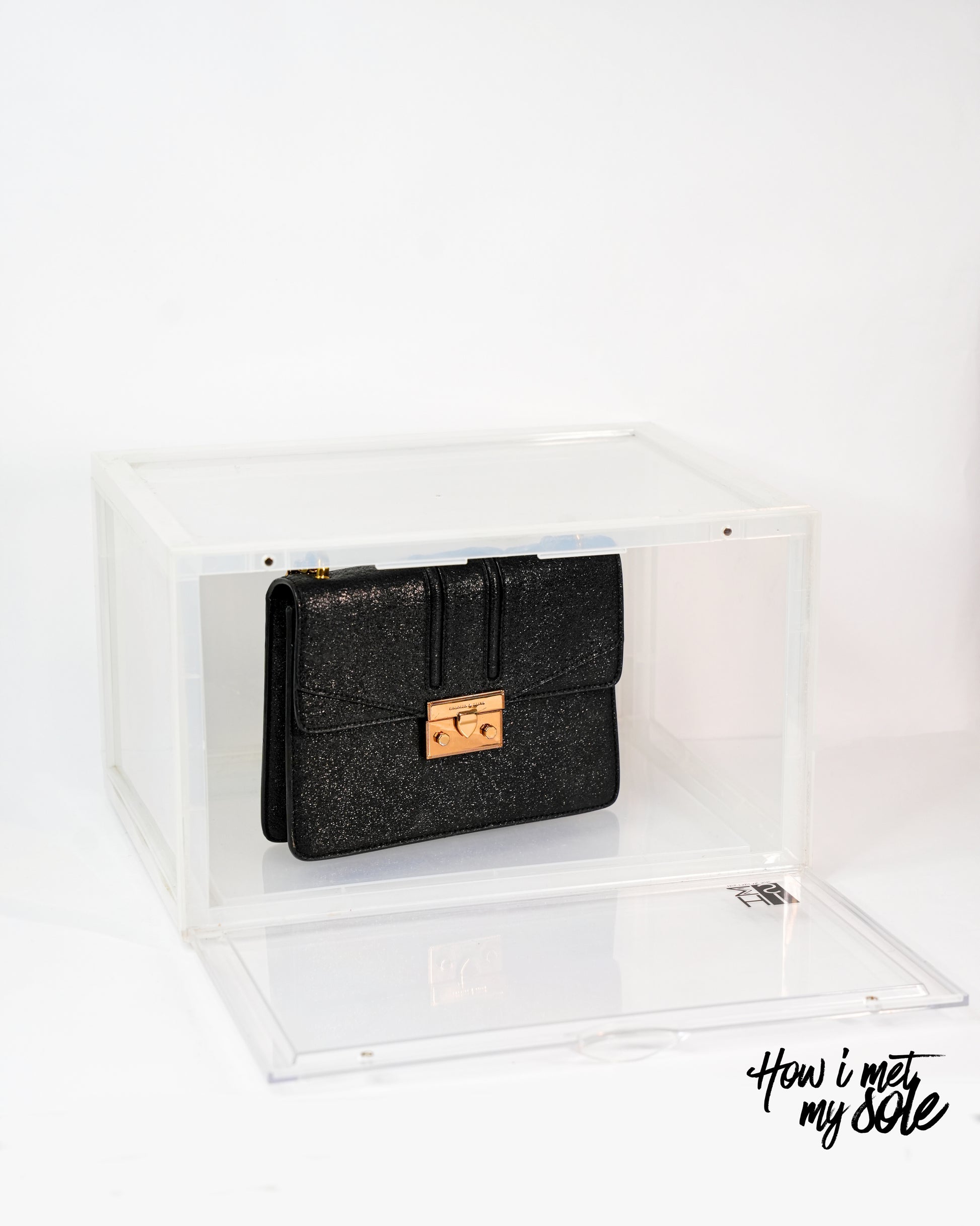 Black clutch bag with gold clasp in a clear style safe storage on a white background