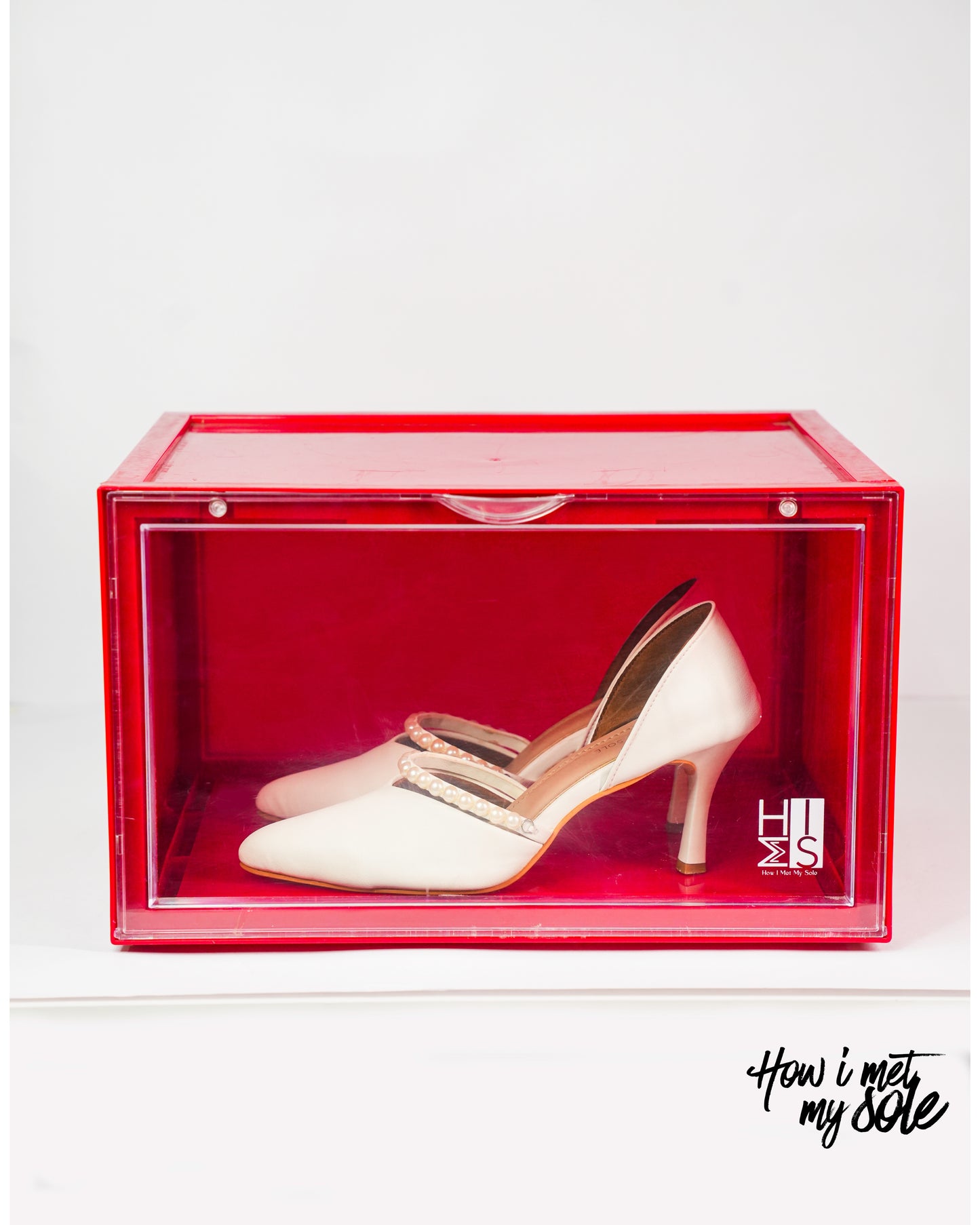 White high-heeled shoe in a red style safe storage box, featuring 'How I Met Your Sole' branding
