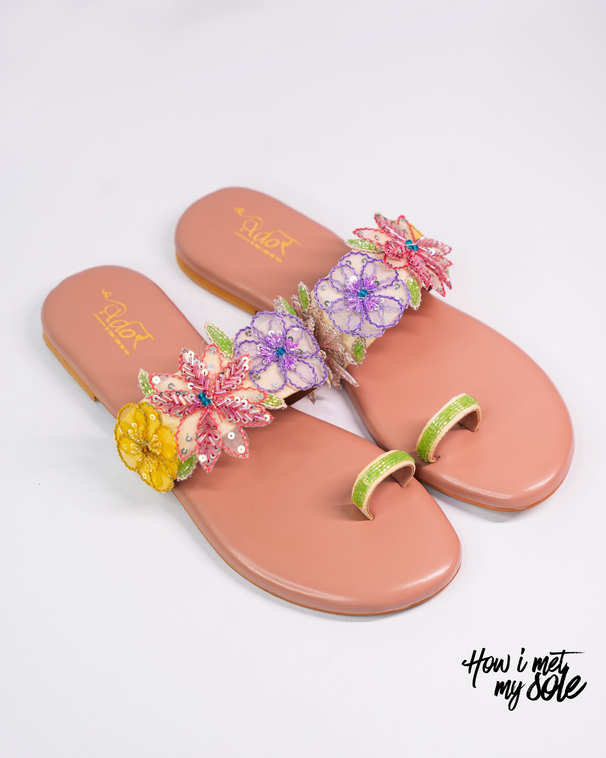 Pair of pink sandals with floral decorations on a white background