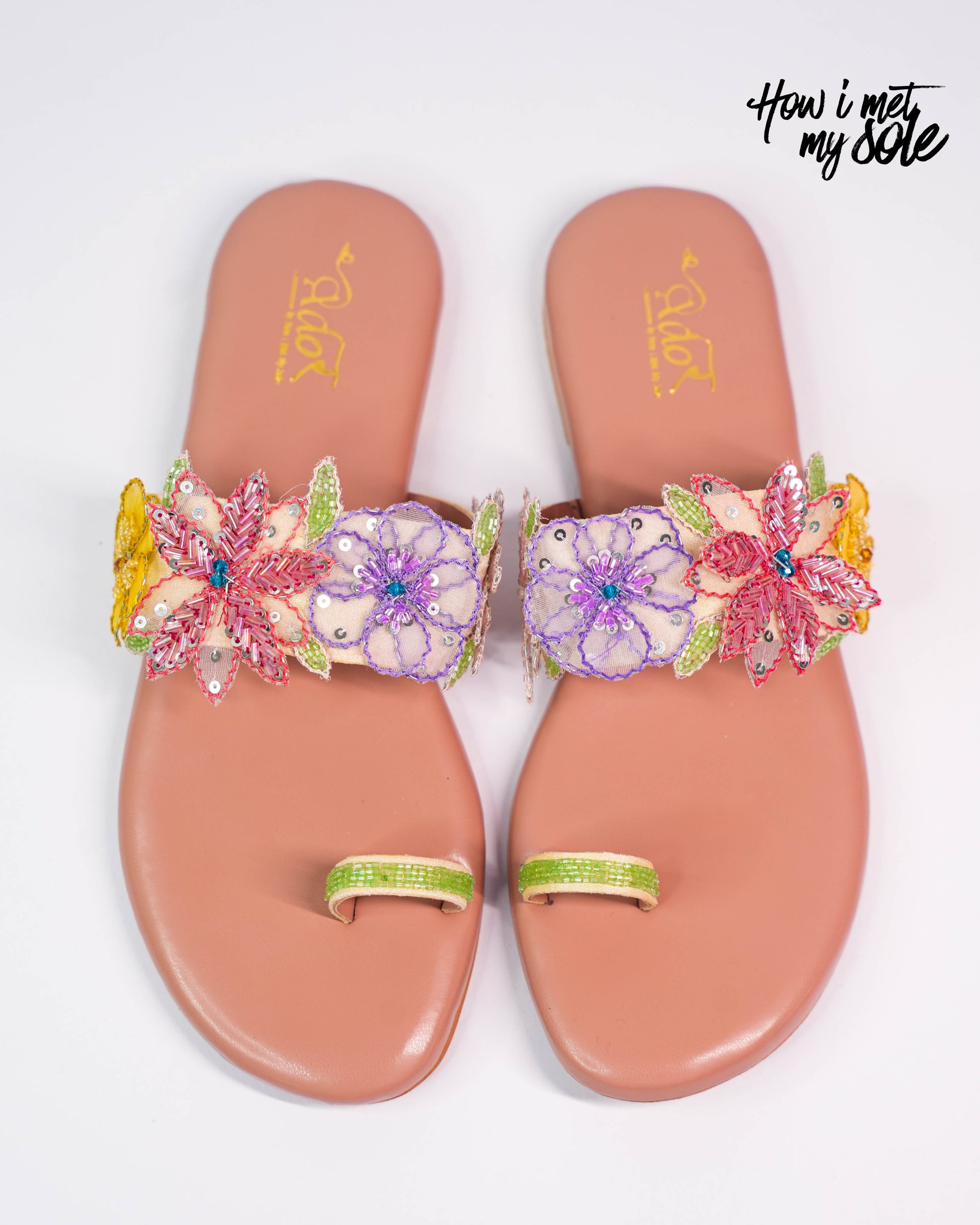 Pair of pink sandals with floral embellishments on a white background