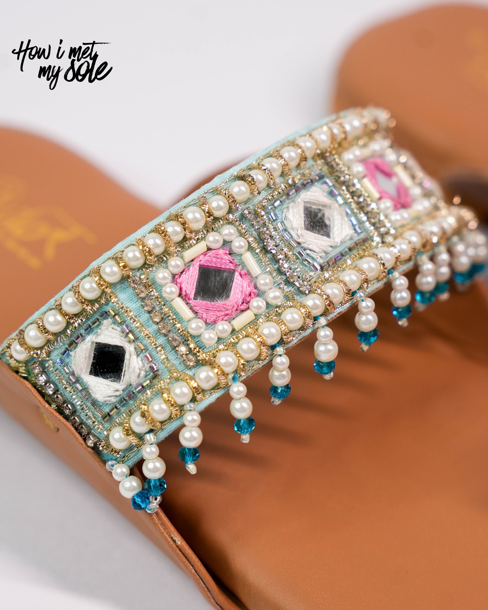 Decorative sandal with pearls and gemstones on a white background